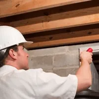Termite inspection technician checking a basement wall and framing for termite activity in Chula Vista, CA